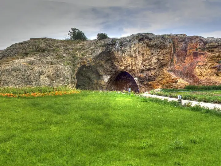 Weathered rock outcrop with a cave opening above a green lawn in Kırşehir's Terme quarter