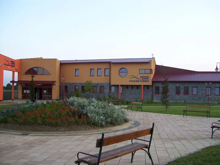 Orange and stone entrance building of the Vulkán thermal bath in Celldömölk with a garden