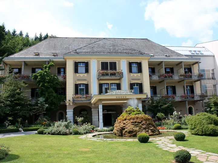 Historic Warmbaderhof spa hotel with balconies and a manicured garden in Warmbad Villach