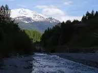 Braulio stream flowing through a wooded valley below snowy peaks near Bormio