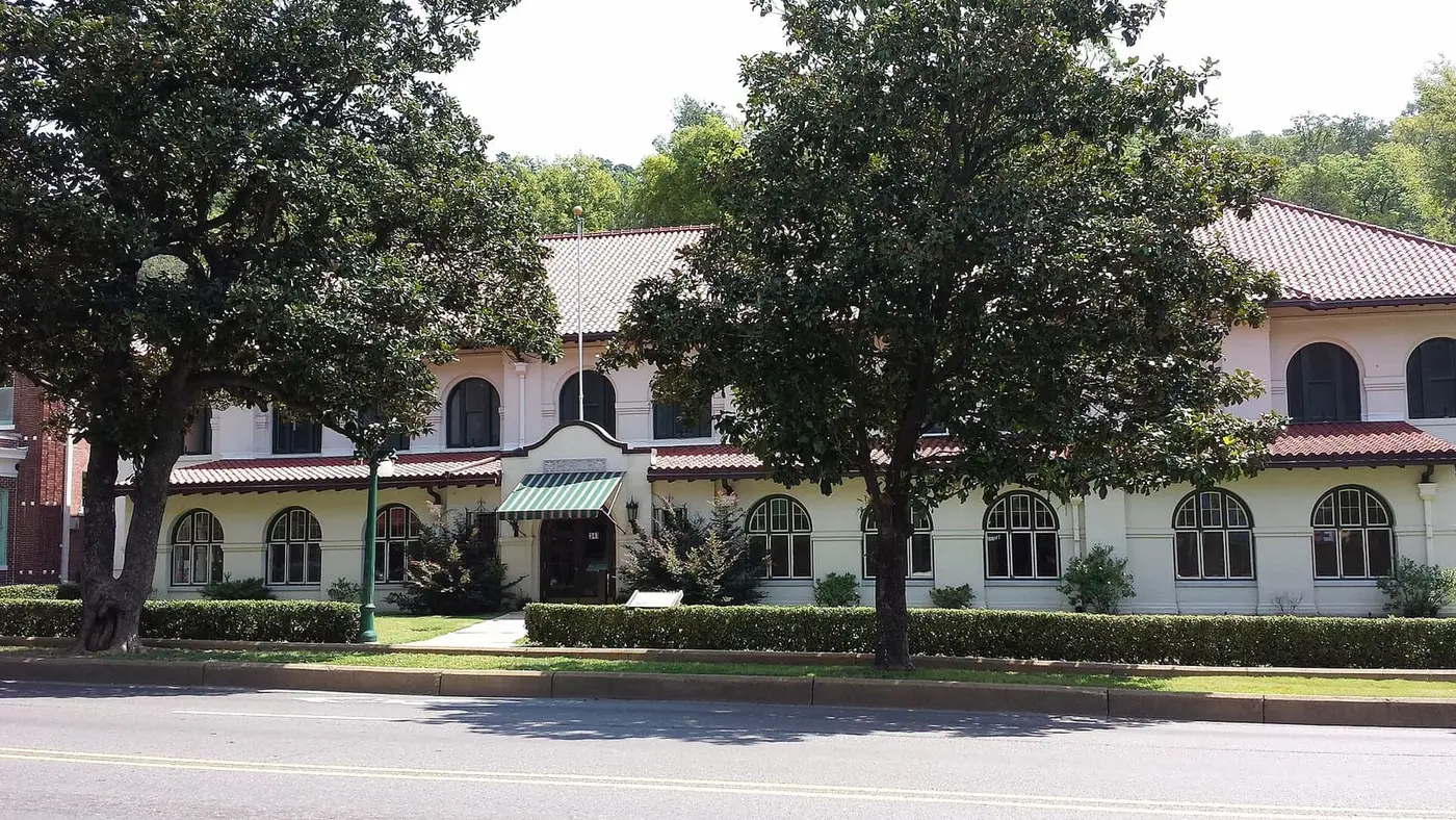 Hale Bathhouse on Bathhouse Row, a cream building with a red tile roof behind large shade trees