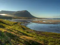 Grassy slope above the tidal flats of Breiðafjörður near Birkimelur, with Hamarshyrna mountain beyond