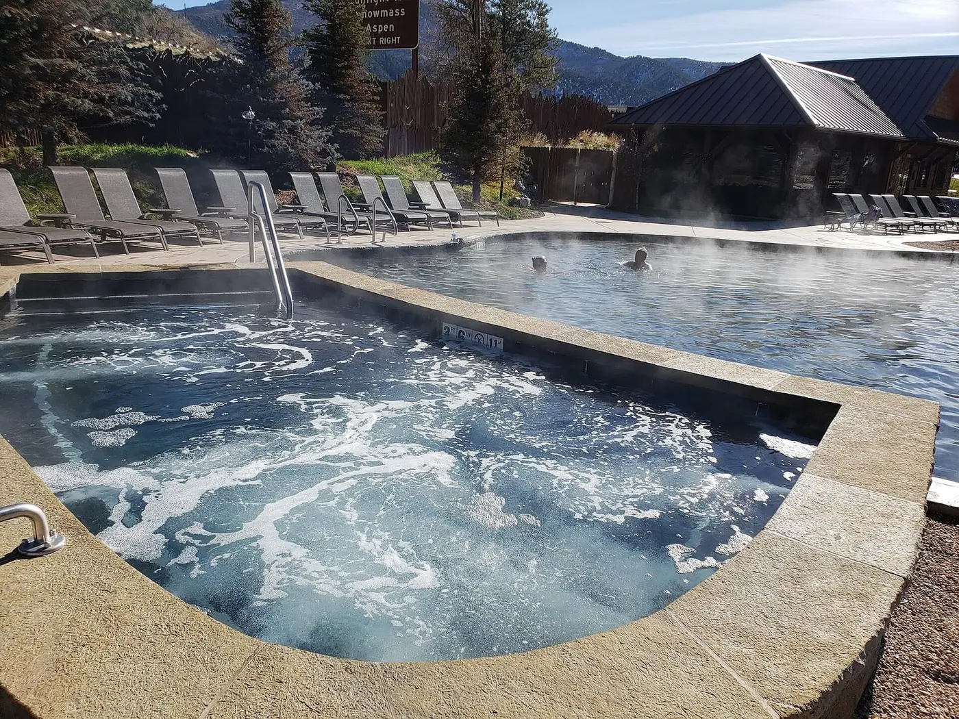 Steaming bubbling soaking pool with lounge chairs at Iron Mountain Hot Springs