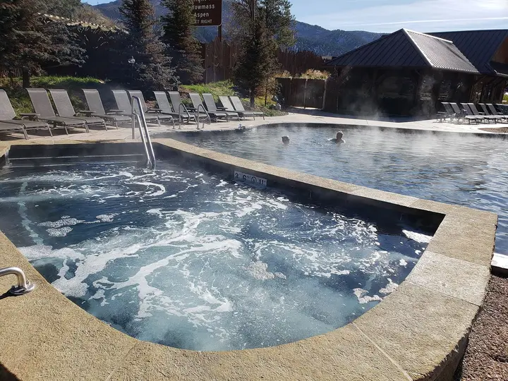 Steaming bubbling soaking pool with lounge chairs at Iron Mountain Hot Springs