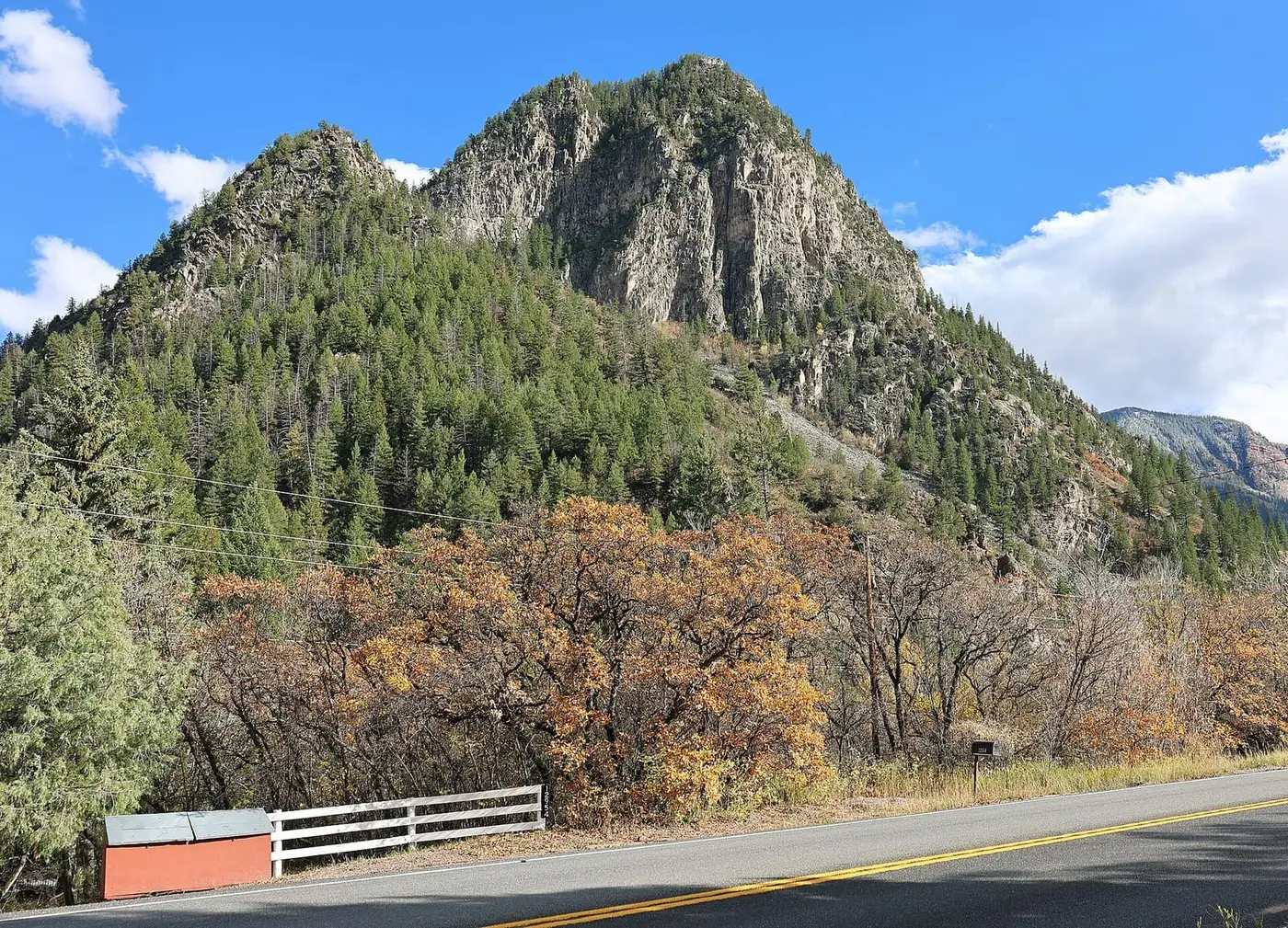 Forested rock peak and autumn oaks above Colorado Highway 133 near Avalanche Road and the ranch