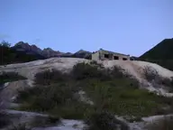 Historic stone bath building on a pale mineral mound at Fairmont Hot Springs with mountains behind