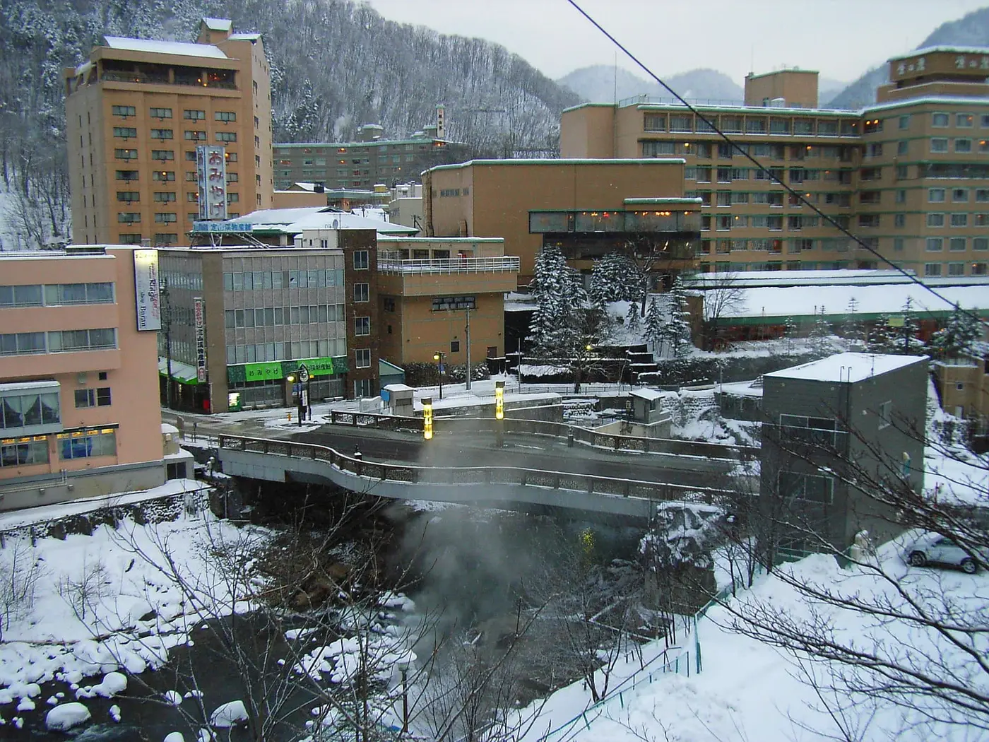 Steam rising from the Toyohira River beneath snowy hotels at Jozankei Onsen in winter
