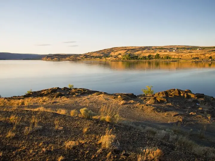 Calm waters of Soap Lake at golden hour seen from its rocky, grassy south shore
