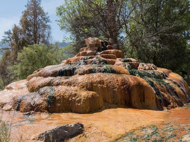 Orange and green mineral mound of Pinkerton Hot Springs among pine trees north of Durango