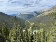 Miette Hot Springs in a forested valley seen from the Sulphur Skyline ridge with peaks beyond