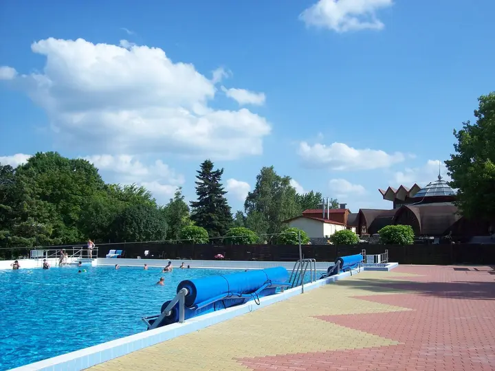 Outdoor thermal pool with a blue slide under a bright summer sky at the Zalakaros bath