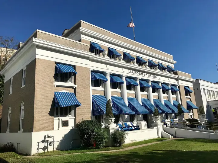 Buckstaff Bathhouse with blue striped awnings and a columned facade under a clear blue sky