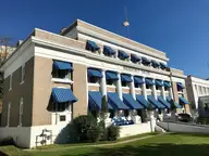Buckstaff Bathhouse with blue striped awnings and a columned facade under a clear blue sky