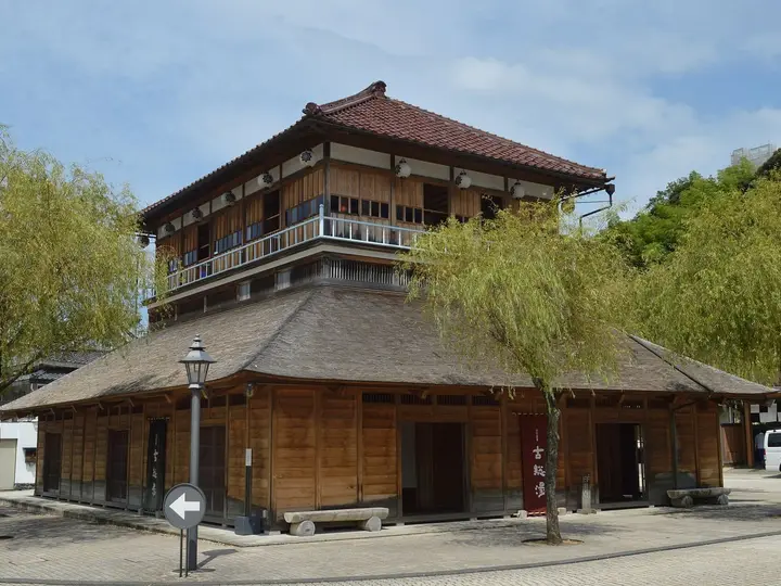 Two storey wooden Kosoyu bathhouse on the square of Yamashiro Onsen with willow trees