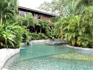 Clear turquoise thermal pool with tiled ledges among tropical plants at Baldi Hot Springs