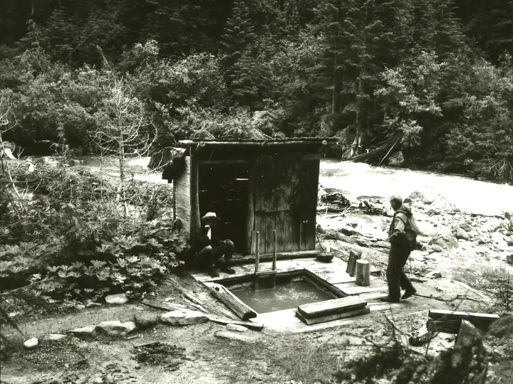 Kennedy Hot Springs in 1963, a wooden soaking pool and plank bathhouse by the White Chuck River, buried in 2003