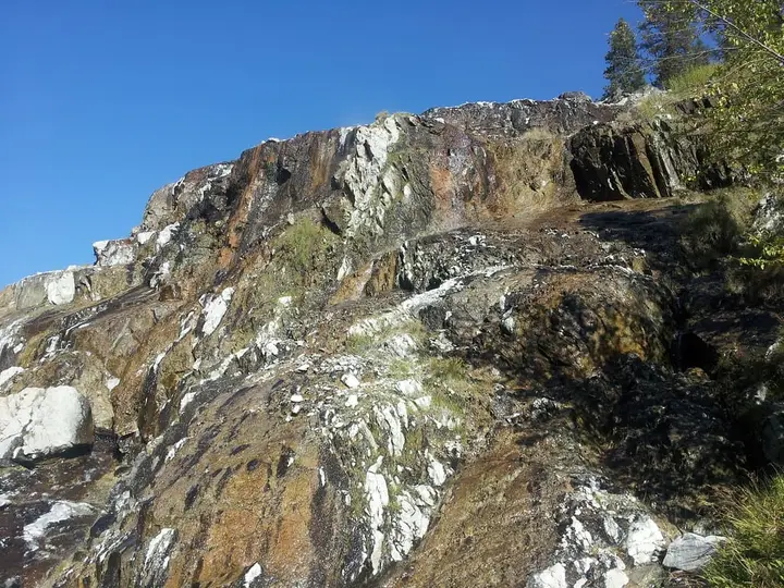 Mineral streaked cliff face at Pine Flats Hot Springs under a clear blue sky