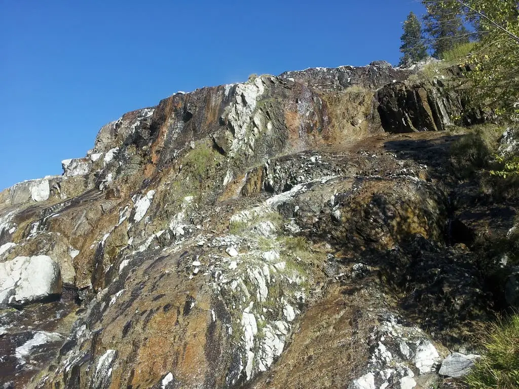 Mineral streaked cliff face at Pine Flats Hot Springs under a clear blue sky