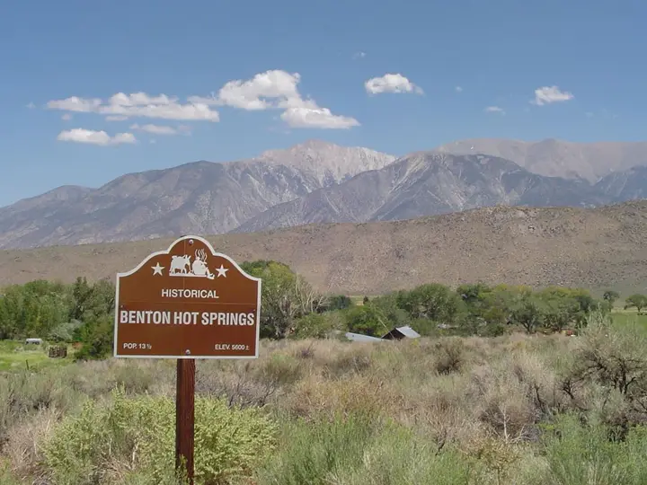 Historical marker sign for Benton Hot Springs in sagebrush below the snowy Eastern Sierra