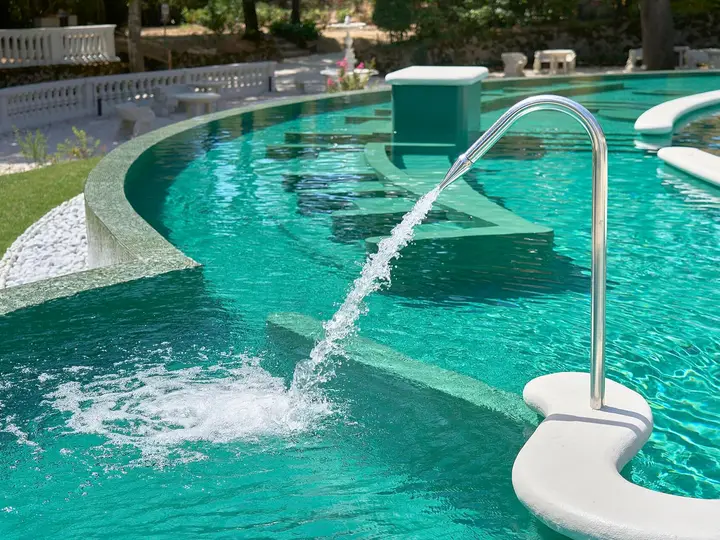Thermal water jet splashing into a turquoise outdoor pool at Terme di Castrocaro