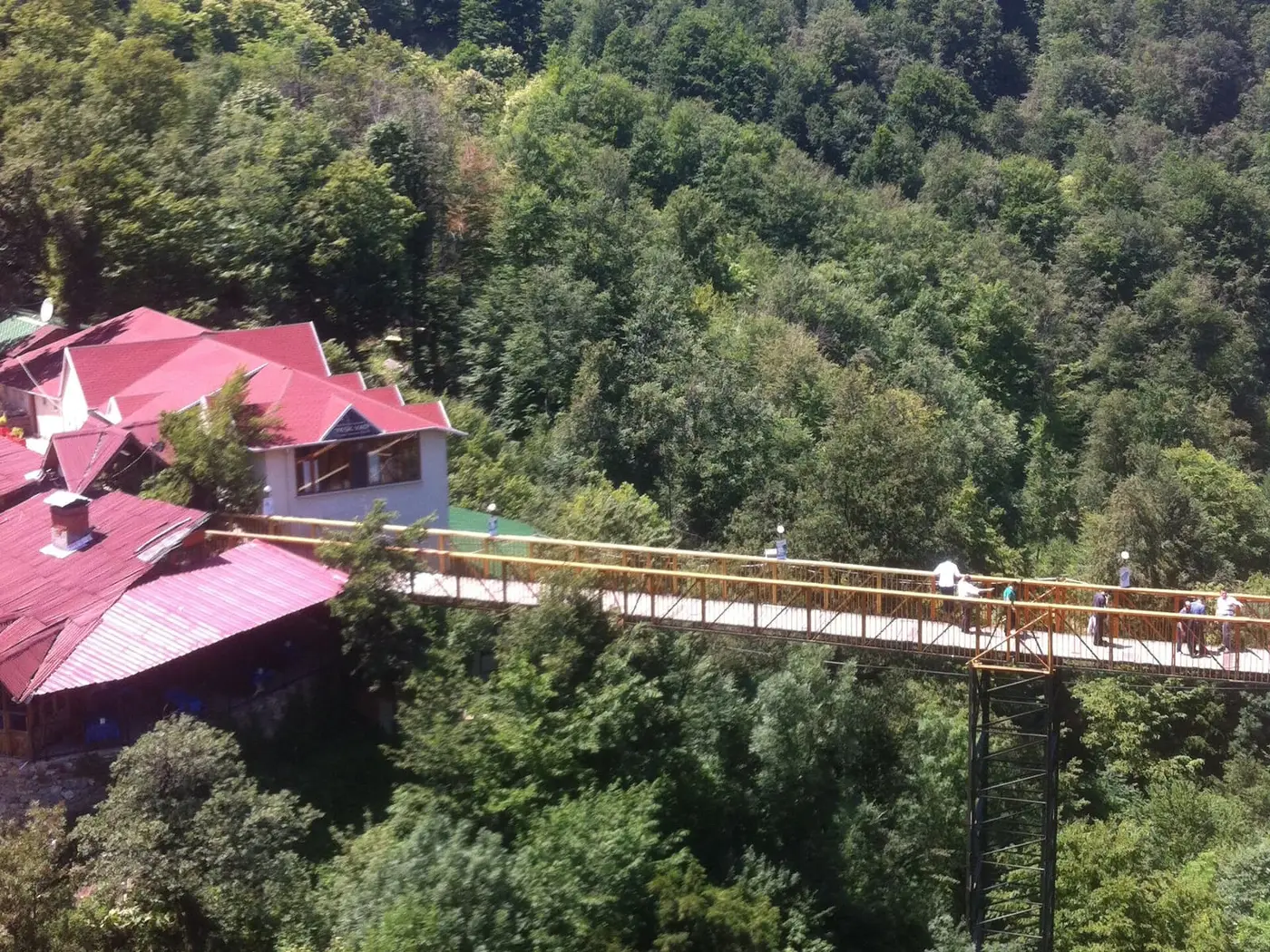 Forested valley at Oylat with the red roofed spa center buildings and a footbridge among the trees