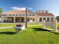 Mammoth Hot Springs Hotel exterior with covered entrance, lawn and Mammoth sign under blue sky