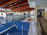 Indoor swimming pool with steps and wooden ceiling beams at Várkertfürdő in Pápa
