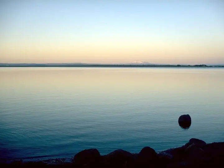 Calm Lake Laugarvatn at dusk with distant mountains on the horizon near Fontana