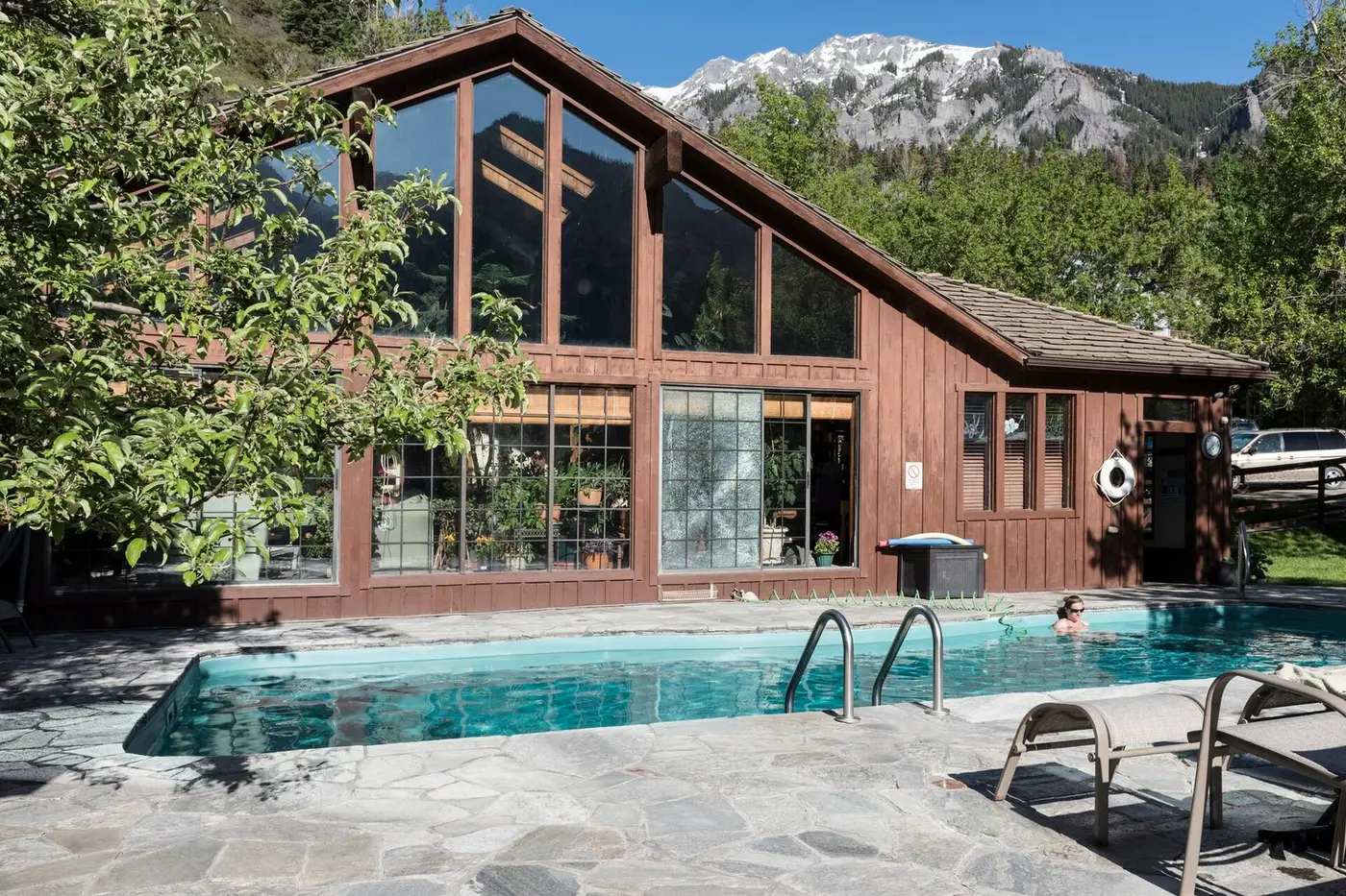Outdoor mineral pool beside the timber and glass lodge at Wiesbaden Hot Springs under mountain peaks in Ouray
