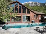 Outdoor mineral pool beside the timber and glass lodge at Wiesbaden Hot Springs under mountain peaks in Ouray