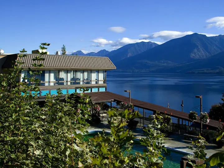 Ainsworth Hot Springs Resort pool below the lodge balcony, with Kootenay Lake and mountains beyond