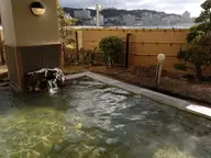Rock lined outdoor hot spring pool at Shirahama Onsen with hotels and the coast beyond