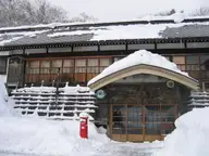 Snow covered wooden facade and entrance of Tsuta Onsen Ryokan in winter