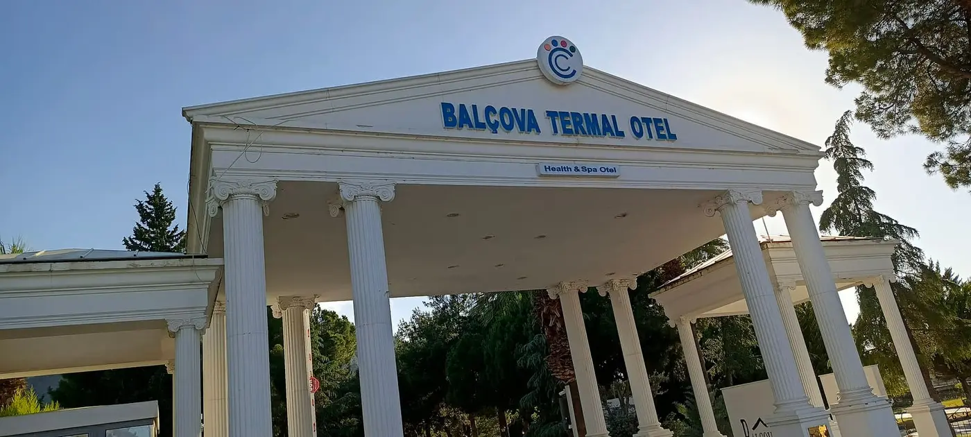 White columned entrance gate of the Balçova Termal Otel under a clear blue sky