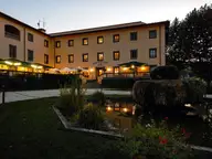 Terme di Stigliano hotel lit at dusk behind a garden pond and fountain
