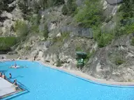 Large blue hot pool at Radium Hot Springs below steep rocky cliffs