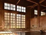 Wooden bath hall at Aoni Onsen with large paned windows and a shallow indoor bath