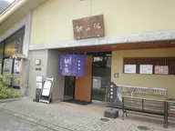 Entrance of Gin no Yu public bathhouse in Arima Onsen with its wooden sign and blue noren