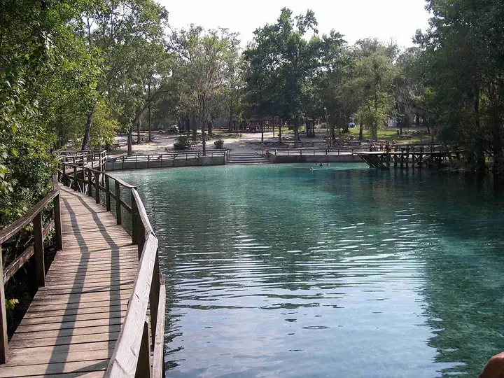 Clear blue Gilchrist Blue Springs pool seen from the wooden boardwalk toward the swimming dock