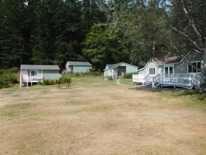 Pale green guest cabins with white decks around a grassy lawn at Doe Bay Resort on Orcas Island