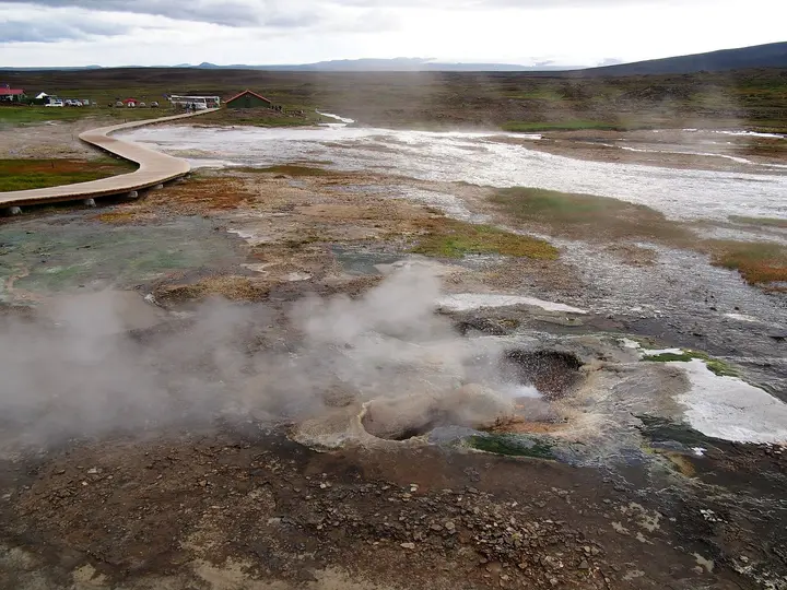 Steaming vents and white sinter crust in the Hveravellir geothermal area with a wooden boardwalk