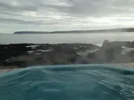 Steaming geothermal hot pot on the Drangsnes shoreline looking across the fjord