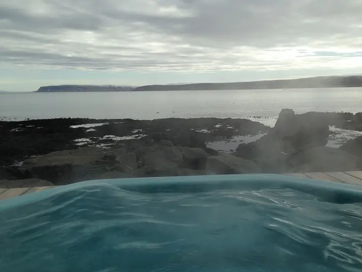 Steaming geothermal hot pot on the Drangsnes shoreline looking across the fjord