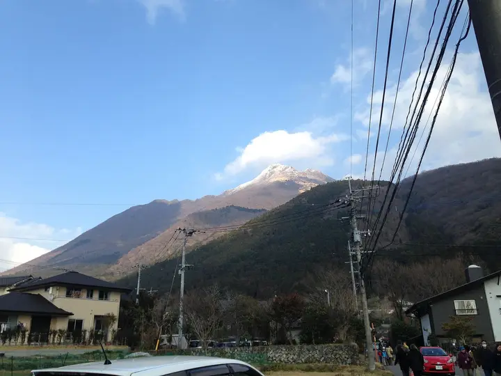 Snow capped Mount Yufu rising above houses along Yunotsubo street in Yufuin Onsen