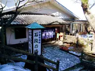 Ishidan no Yu public bathhouse at Ikaho Onsen with its tall wooden sign and light snow