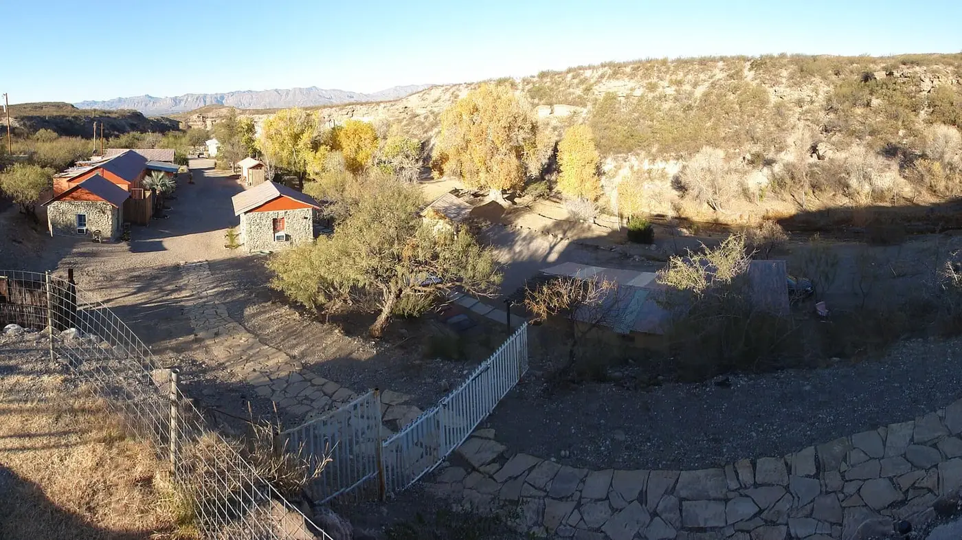 Stone cabins and autumn cottonwoods at Chinati Hot Springs in a desert canyon near Ruidosa
