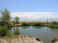 Reed lined warm pool at Saratoga Hot Springs on the shore of Utah Lake below snowy Wasatch peaks