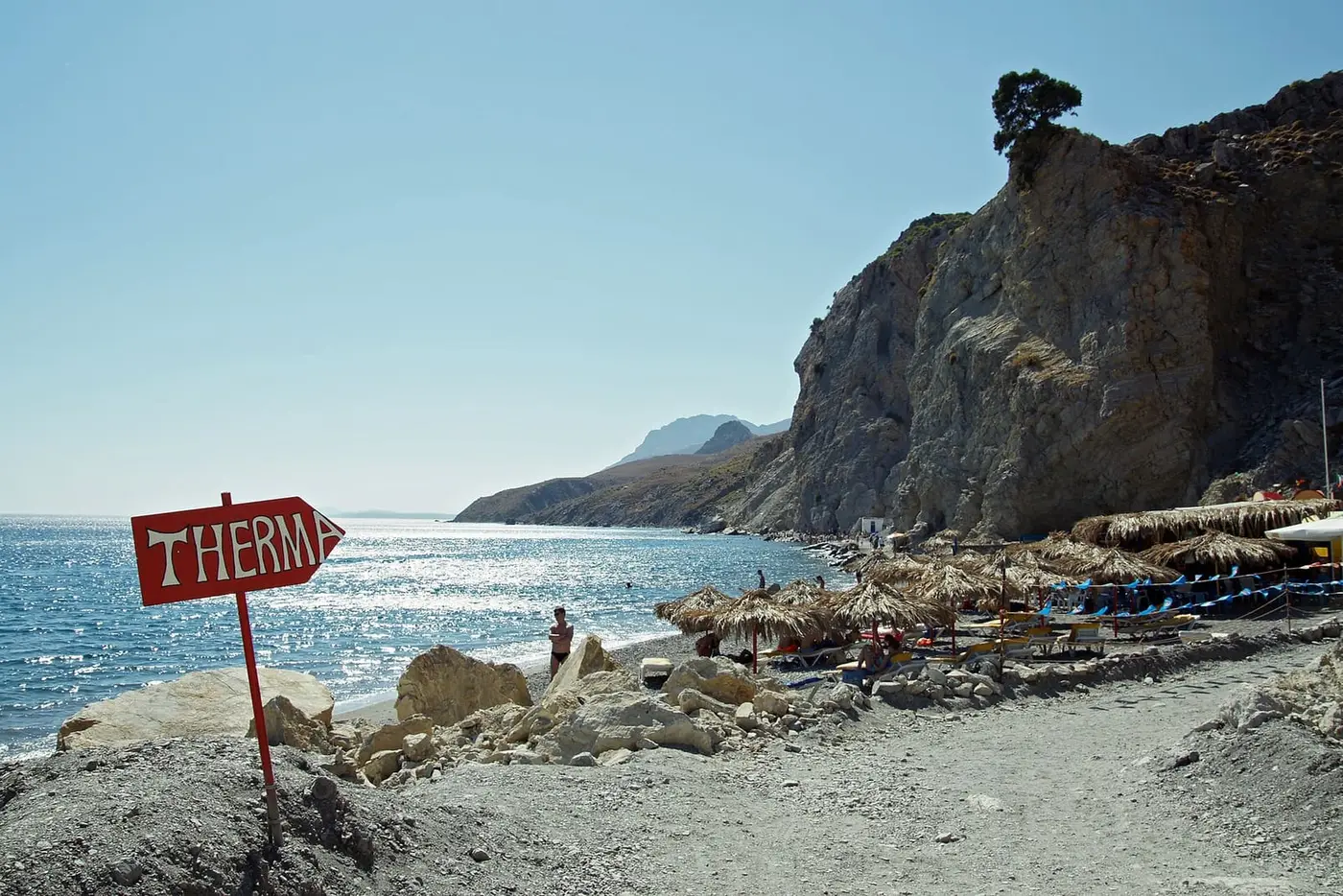 Red Therma sign on the pebble beach below the cliffs of south east Kos