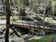 Wooden footbridge over a rocky creek on the wooded grounds of Orr Hot Springs Resort