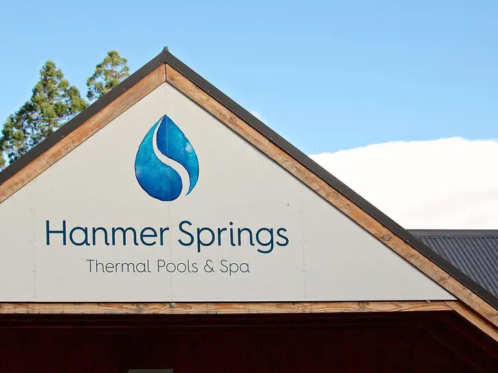 Gabled entrance building with the Hanmer Springs Thermal Pools and Spa sign under blue sky